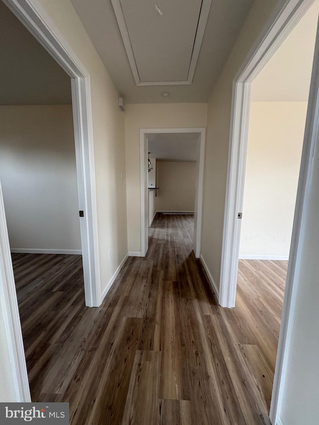 hall featuring dark wood finished floors, attic access, and baseboards