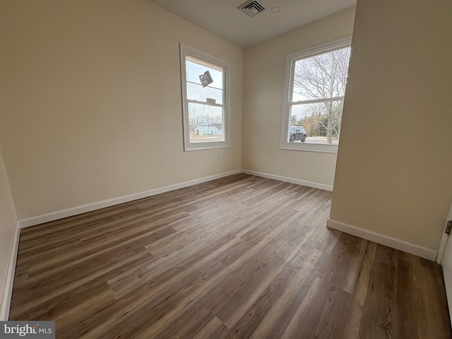 empty room featuring visible vents, baseboards, and wood finished floors