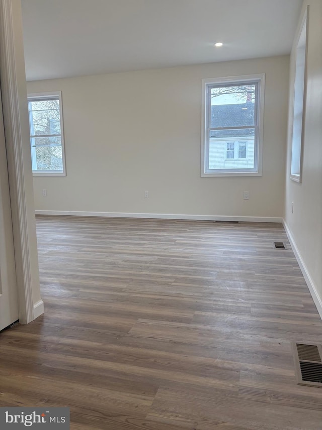 unfurnished room with visible vents, baseboards, and wood finished floors