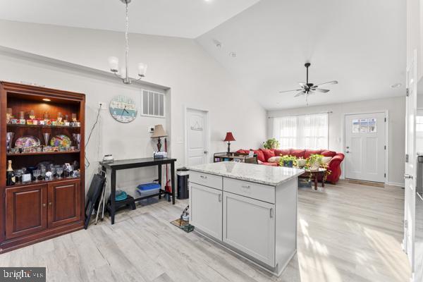 kitchen with a center island, visible vents, light wood-style floors, open floor plan, and ceiling fan with notable chandelier