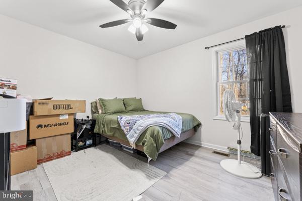 bedroom featuring ceiling fan, light wood-style flooring, and baseboards