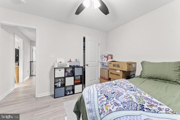 bedroom with ceiling fan, light wood-style flooring, and baseboards