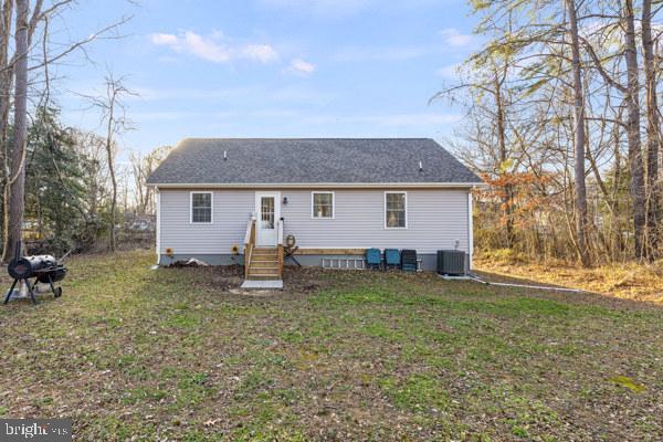 back of house with entry steps, central air condition unit, and a yard