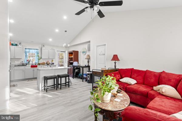 living room with light wood-type flooring, high vaulted ceiling, a ceiling fan, and recessed lighting