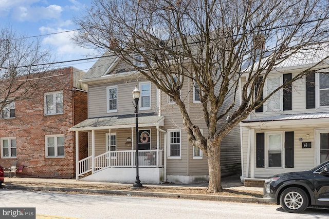 multi unit property with a porch and roof with shingles