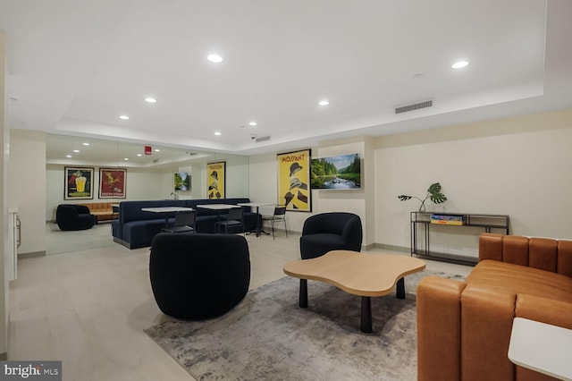 living area featuring a tray ceiling, visible vents, and recessed lighting