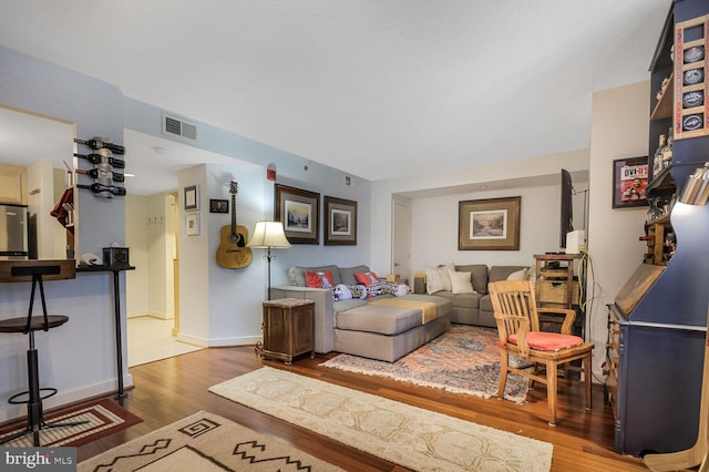 living area featuring visible vents, baseboards, and wood finished floors