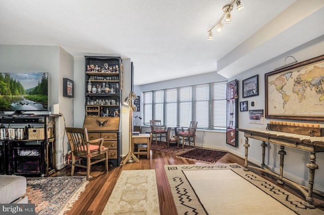 living area with a textured ceiling, baseboards, and wood finished floors