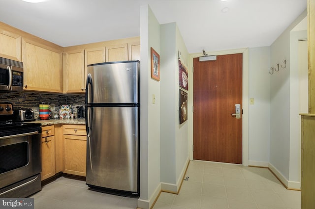 kitchen with baseboards, stainless steel appliances, light brown cabinets, and decorative backsplash