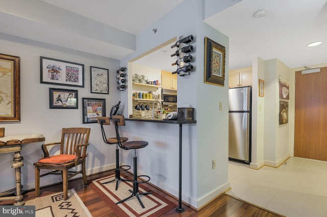 bar featuring appliances with stainless steel finishes, wood finished floors, a dry bar, and baseboards