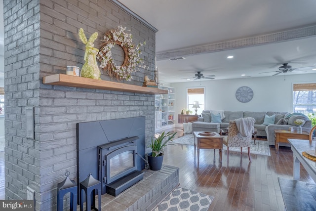 living room with visible vents, recessed lighting, a wood stove, a ceiling fan, and wood-type flooring