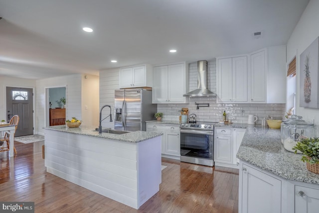 kitchen featuring a sink, white cabinets, stainless steel appliances, wall chimney exhaust hood, and dark wood-style flooring