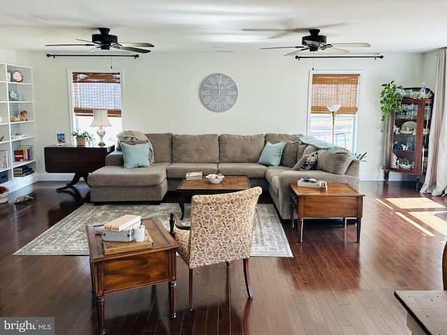 living area with baseboards, a healthy amount of sunlight, and dark wood-style flooring