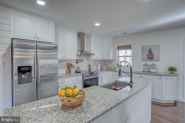 kitchen featuring a sink, stainless steel appliances, white cabinetry, wall chimney exhaust hood, and backsplash