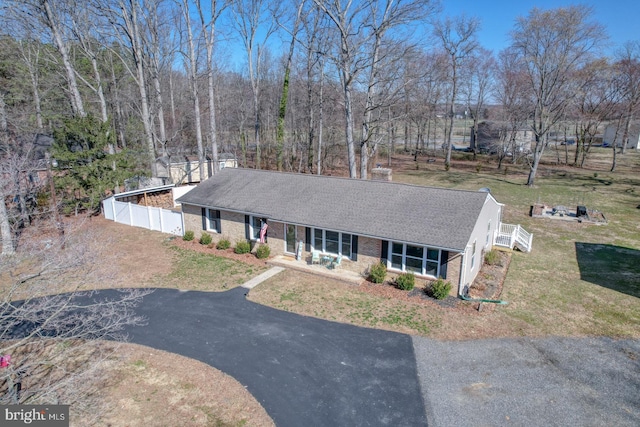 view of front of home with aphalt driveway, brick siding, a porch, and fence