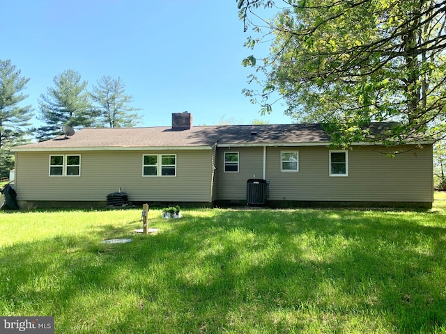 rear view of house with a lawn, central AC, and a chimney