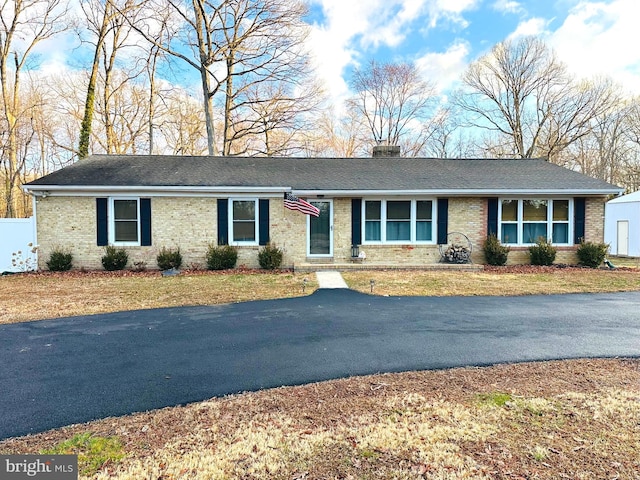 single story home with a front yard, brick siding, and a chimney