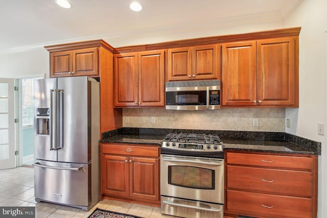 kitchen featuring dark stone counters, stainless steel appliances, decorative backsplash, and crown molding