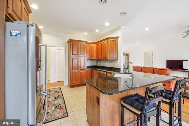 kitchen featuring a breakfast bar area, stainless steel appliances, a peninsula, a sink, and tasteful backsplash