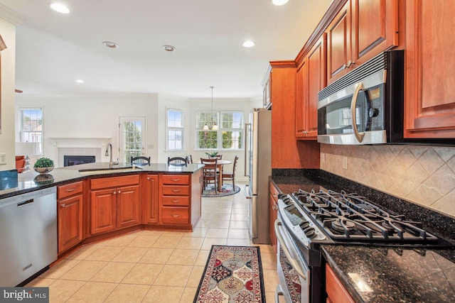 kitchen with light tile patterned floors, a tile fireplace, a sink, appliances with stainless steel finishes, and tasteful backsplash