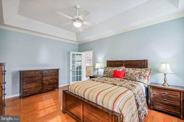 bedroom with wood finished floors, a raised ceiling, and baseboards