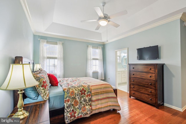 bedroom with a tray ceiling, multiple windows, and hardwood / wood-style floors