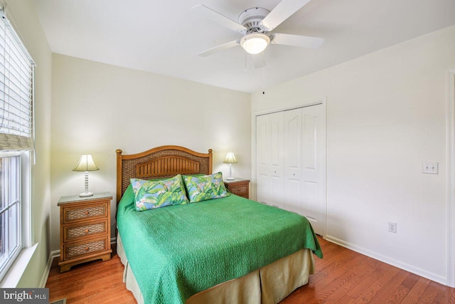 bedroom with a closet, wood finished floors, a ceiling fan, and baseboards