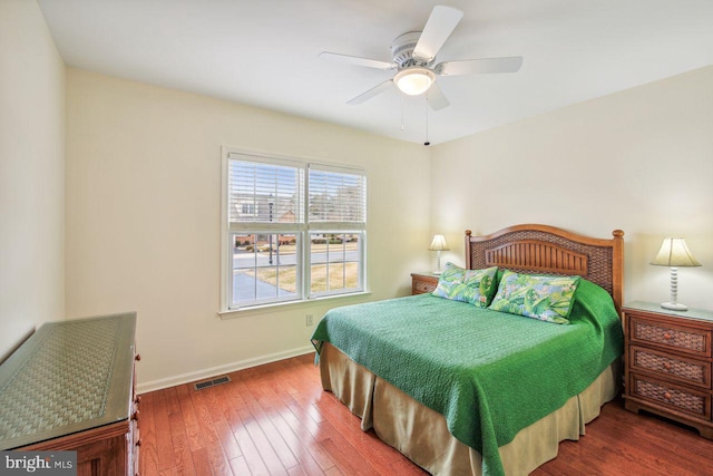 bedroom with a ceiling fan, wood-type flooring, visible vents, and baseboards