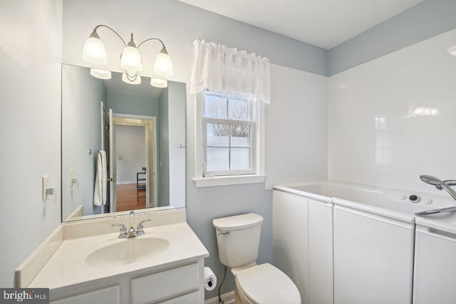 bathroom featuring vanity, toilet, and a bath