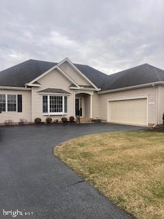 ranch-style home featuring driveway, a garage, and a front yard