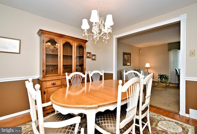 dining space with a chandelier, wood finished floors, visible vents, and baseboards