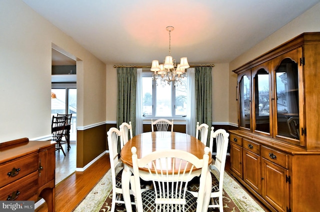 dining room featuring a wealth of natural light, wainscoting, light wood-style flooring, and an inviting chandelier