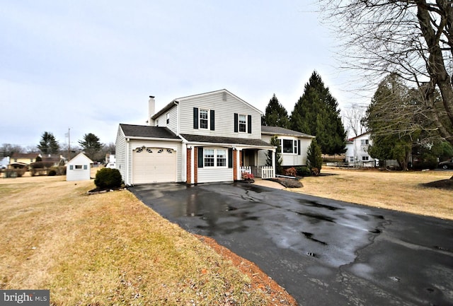 view of front of house featuring driveway, a chimney, an attached garage, a front yard, and brick siding