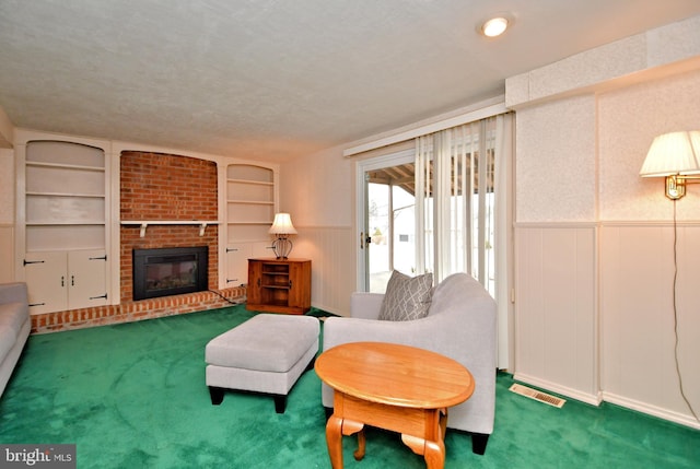 living area featuring built in shelves, a wainscoted wall, visible vents, a brick fireplace, and carpet