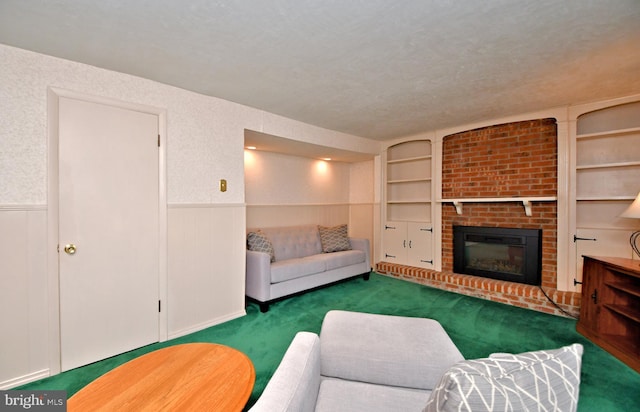 carpeted living area featuring built in shelves, wainscoting, a fireplace, and a textured ceiling