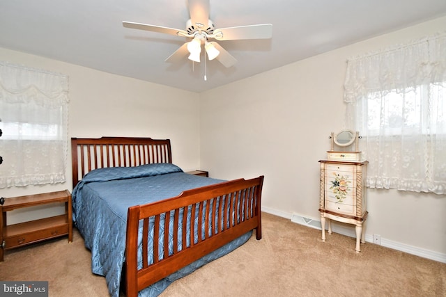 carpeted bedroom with visible vents, baseboards, and a ceiling fan