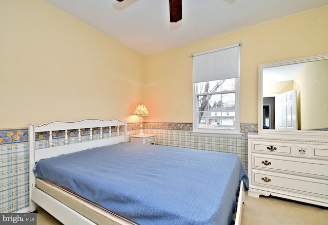 bedroom with wainscoting, carpet flooring, and a ceiling fan