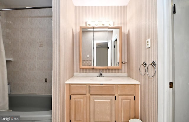 bathroom featuring tub / shower combination, vanity, and wallpapered walls