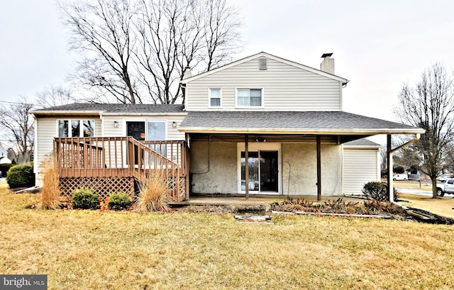 back of house featuring roof with shingles, a lawn, a chimney, and a wooden deck