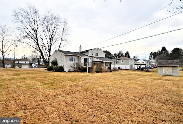 back of house featuring an outbuilding, a lawn, a deck, and a storage unit