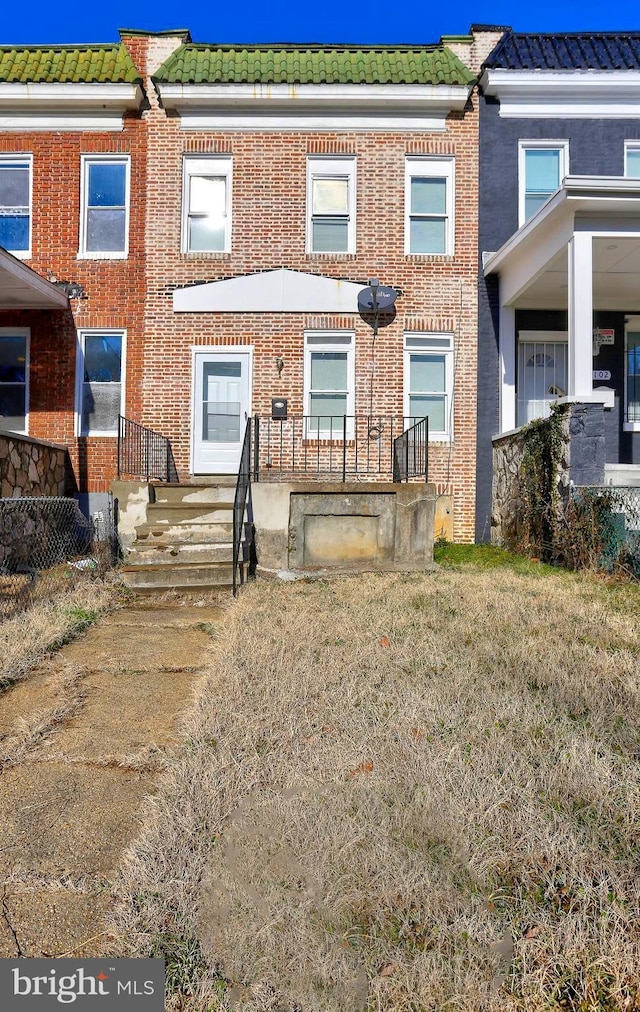 townhome / multi-family property with brick siding and a tile roof