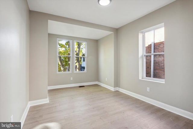 unfurnished room with wood finished floors, visible vents, and baseboards