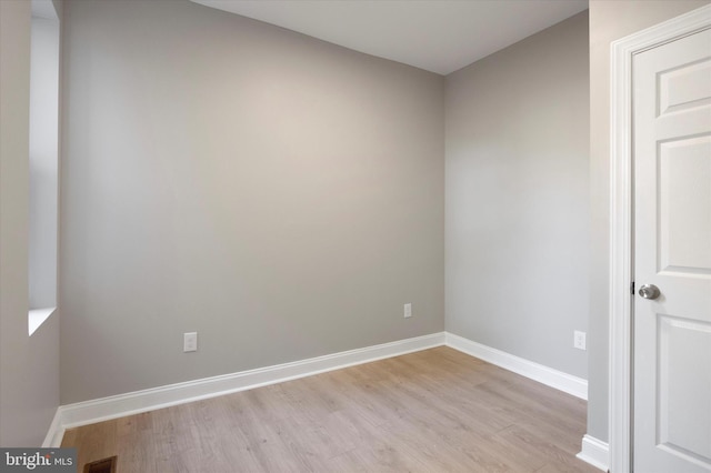 spare room featuring light wood finished floors, visible vents, and baseboards