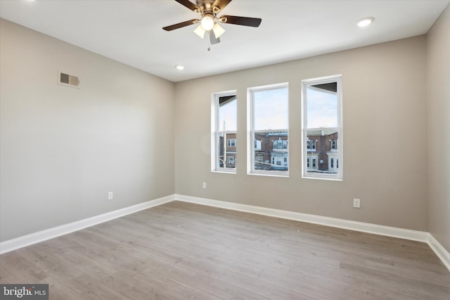 spare room with a ceiling fan, visible vents, baseboards, and wood finished floors