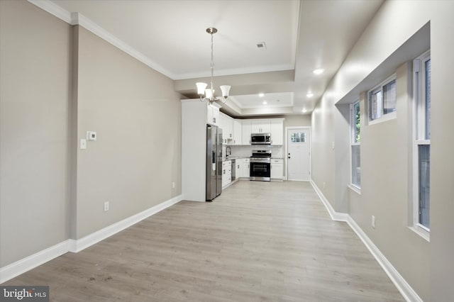 kitchen featuring light wood finished floors, appliances with stainless steel finishes, baseboards, and crown molding