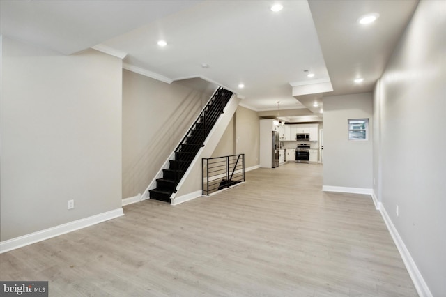 basement with light wood-type flooring, baseboards, and crown molding