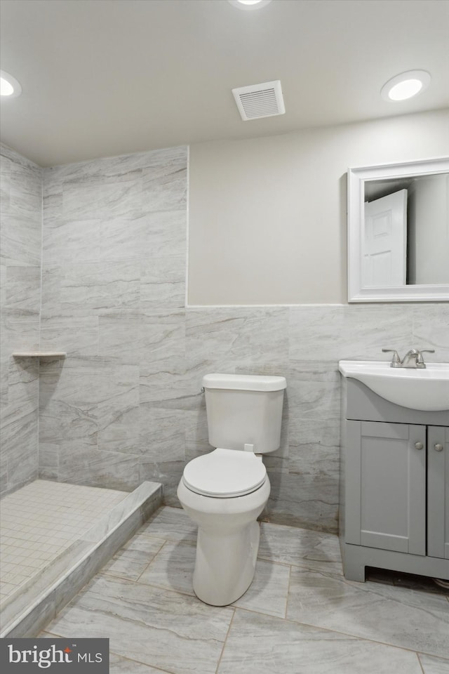 full bathroom featuring tile walls, visible vents, toilet, vanity, and tiled shower