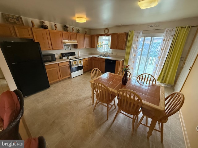 kitchen with black appliances, under cabinet range hood, light countertops, and a sink