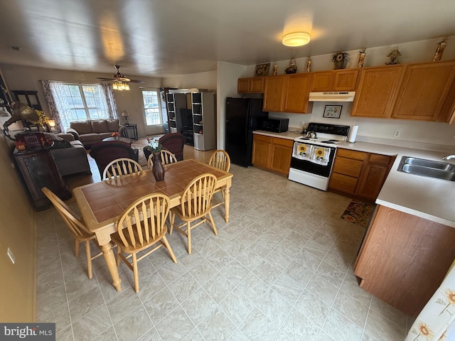 kitchen featuring white range with electric stovetop, light countertops, freestanding refrigerator, a sink, and under cabinet range hood