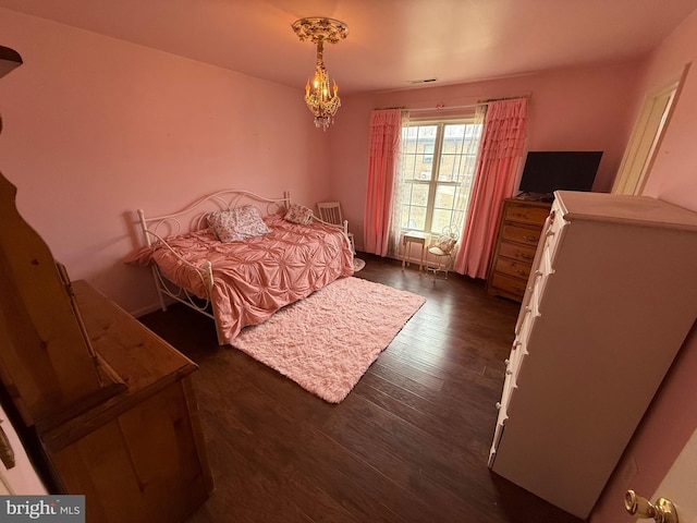 bedroom featuring a notable chandelier and dark wood finished floors